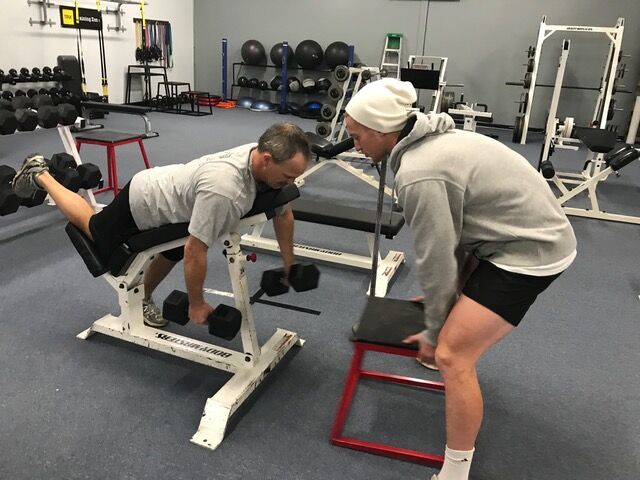 A trainer coaching a member on a row